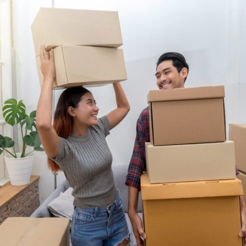 Asian young couple carrying big cardboard box for moving in new house, Moving and House Hunting concept, selective focus